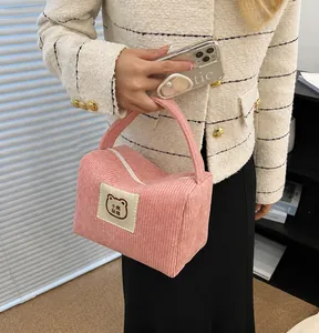 Borsa da trucco in velluto a coste rosa con toppa a forma di orso, portata da una modella