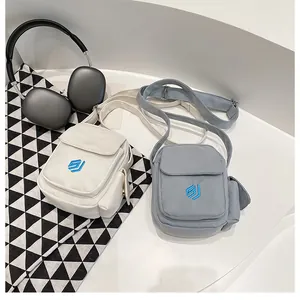 Detail of mini canvas crossbody bags in beige and blue with flap and embroidery