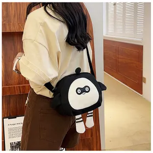 Detail view showing a black canvas crossbody bag with cartoon monster face and legs
