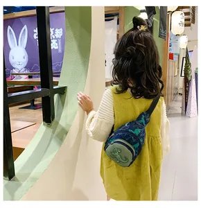 Détail de la banane enfant bleue avec motifs de dinosaures verts sur une enfant