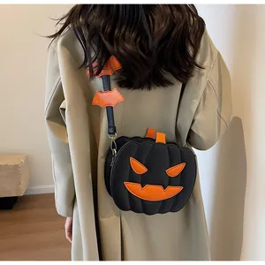 Detail of a Halloween pumpkin crossbody bag with orange bat straps worn by a model