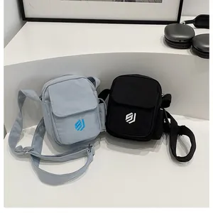 Detail of compact outdoor crossbody bags in light blue and black with embroidered logo