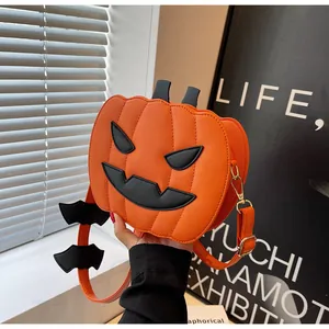 Detail of pumpkin crossbody bag featuring black bat strap ornament and lychee leather