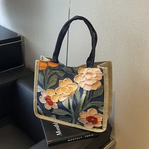 Gros plan du sac fourre-tout fleuri montrant les motifs oranges et le côté en lin
