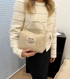 Dettaglio borsa beige in velluto a coste con ricamo a orsetto e tracolla regolabile