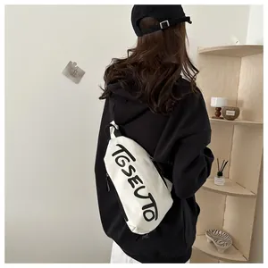 Détail du sac de poitrine en toile blanche avec texte TGSEUTO et sangle en nylon