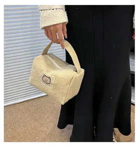 Dettaglio di una pochette in velluto a coste beige con toppa a forma di orsetto