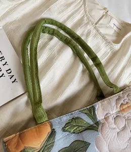 Détail des anses en toile et de l'imprimé floral vintage sur un grand sac cabas