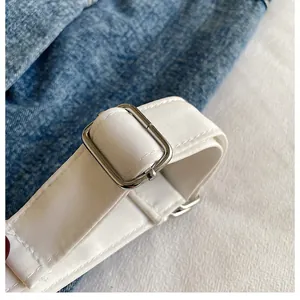 Close-up of white woven strap with silver metal buckle on a compact outdoor bag