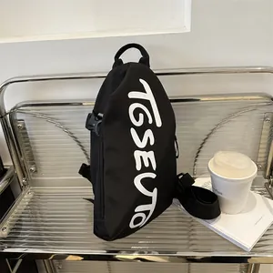 Borsa a tracolla nera moderna con scritte grafiche bianche su una sedia minimalista