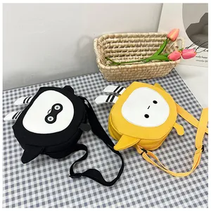 Detail of cute cartoon canvas crossbody bags in black and yellow on a picnic mat
