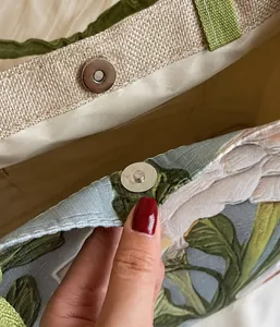 Détail du fermoir magnétique en métal et de la texture du tissu tissé à fleurs