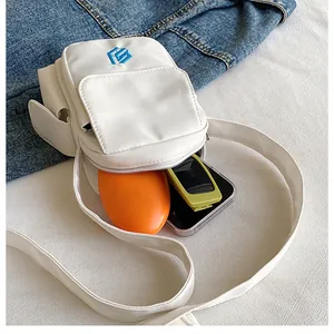 Detailed view of mini white nylon crossbody bag showing interior storage for phone and glasses