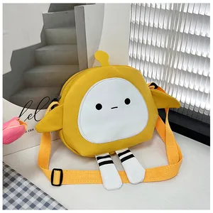 Detailed view of yellow canvas bag featuring cute cartoon face and hanging leg charms