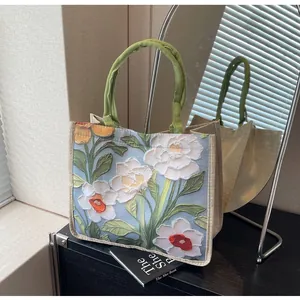 Détail de la broderie florale sur tote bag en jute beige avec poignées vertes