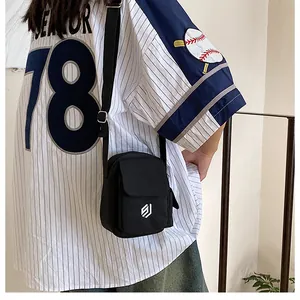 Close-up of a black canvas crossbody bag featuring a white logo and adjustable strap