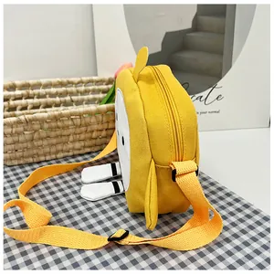 Detailed side view of yellow cartoon canvas crossbody bag with small wings and 3D feet