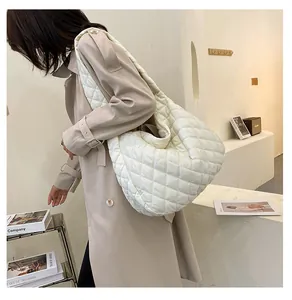 Foto lifestyle di una grande borsa tote trapuntata bianca con motivo a rombi su modella