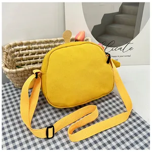 Close-up of a yellow canvas crossbody bag with adjustable strap on a checkered fabric