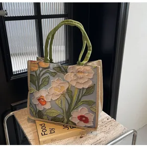 Détail d'un sac cabas avec imprimé floral 3D, poignées tissées et texture en lin