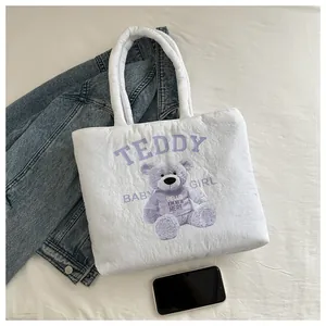 Detailed macro view of white quilted tote bag featuring a cute purple teddy bear pattern
