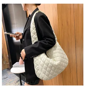Modella indossa una borsa hobo trapuntata color crema su un blazer nero per un look chic