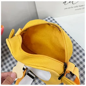 Detail view of the yellow canvas shoulder bag showing zipper closure and internal storage