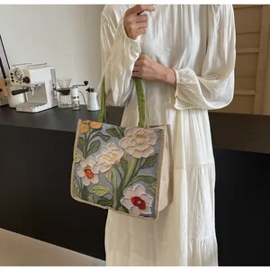 Détail de la broderie florale en relief sur un grand sac cabas en toile pour femme
