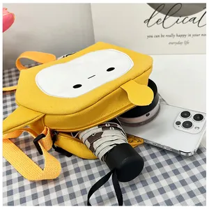 Detail view showing storage capacity of the yellow cartoon canvas bag with a phone and umbrella