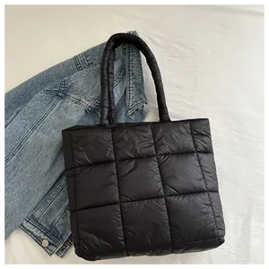 Detail of the black quilted padded tote bag on white fabric with a blue denim jacket