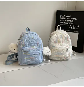 Detailed close-up of quilted light blue and off-white mini backpacks with cloud charms