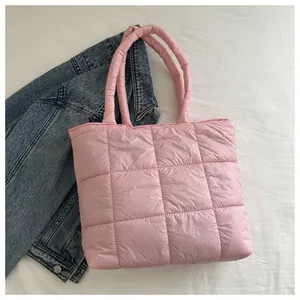 Detailed top view of pink quilted puffer tote bag with padded handles on white fabric