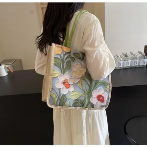 Détail de la texture brodée du grand sac cabas fleuri avec des anses vertes