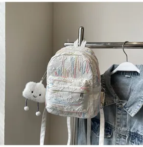 Close-up of white quilted mini backpack with colorful embroidery and plush cloud charm