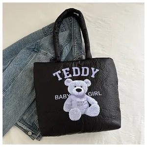 Close-up of black quilted nylon tote bag with cute purple teddy bear print and text