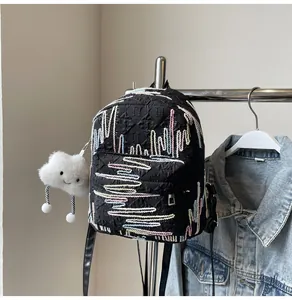 Detail of black mini backpack with colorful wavy embroidery and white cloud plush charm
