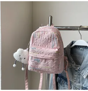 Detail of pink quilted backpack with colorful embroidery and cute white cloud charm
