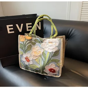 Détail de motifs floraux en relief sur un sac cabas en lin à poignées tissées