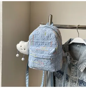 Detail of light blue textured backpack with zigzag embroidery and plush cloud charm