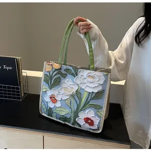 Gros plan sur la broderie florale 3D sur un sac cabas en jute avec poignées vertes