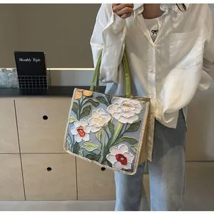 Détail de la broderie florale 3D sur un sac cabas en lin avec des anses vertes