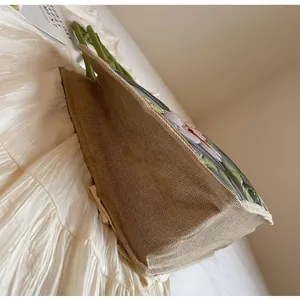 Détail du sac cabas en jute à motif floral montrant la texture et les poignées vertes