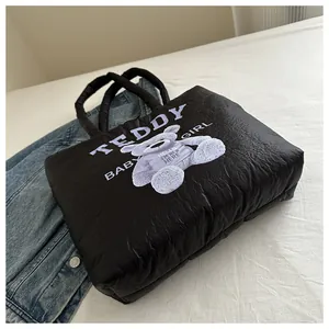 Close-up of black quilted puffer tote bag featuring a cute purple teddy bear print