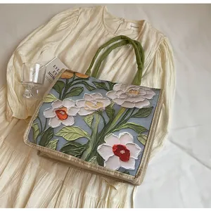 Détail de la broderie florale 3D et des anses tissées vertes sur le grand sac cabas
