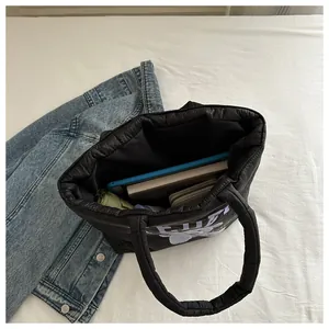 Macro view of spacious black quilted tote interior holding tablet, notebook and umbrella