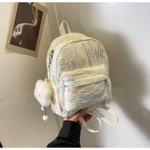 Detail of white mini backpack with colorful wave embroidery and plush cloud charm