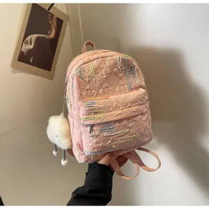 Detail of pink quilted backpack featuring colorful embroidery and a soft cloud charm