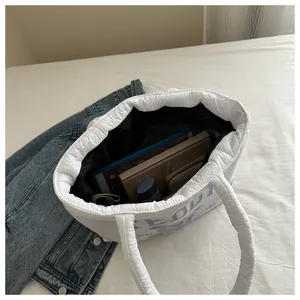 Spacious interior of white quilted tote bag showing tablet, wallet, and cosmetics storage