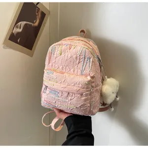 Detail of pink backpack with embossed fabric texture and a cute white pom-pom charm