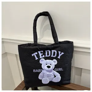 Detail of black quilted canvas tote featuring a purple teddy bear and letter printing